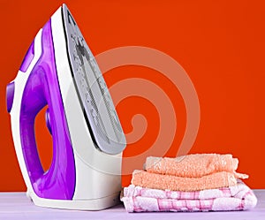 Pile of colorful clothes and irons, on pastel wooden plank ,yellow color background.