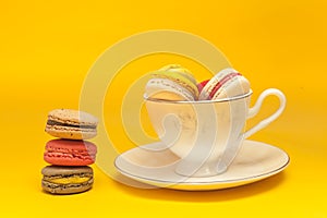 Pile of colorful macarons stacked up in the white classic cup in