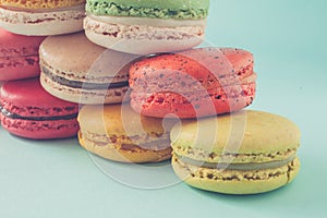Pile of colorful macaroons stacked up like a tower in turquose pastel background (Selective focus) - Closeup. photo