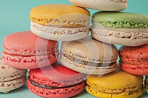Pile of colorful macaroons stacked up like a tower in turquose pastel background (Selective focus) - Closeup photo