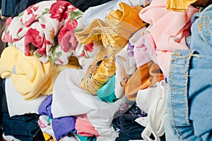 Pile of colorful messy clothes in closet. Untidy cluttered woman by side view.