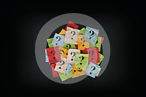 Pile of colorful paper notes with question marks on blackboard