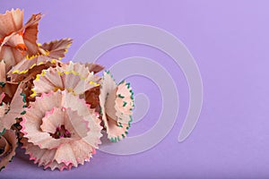 Pile of colorful pencil shavings on violet background, closeup. Space for text