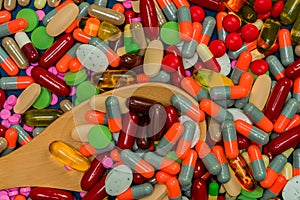 Pile of colorful pills and wood spoon. Medicine, vitamins, supplement and minerals. Antibiotics drug resistance and drug use