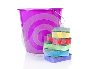 Pile of colorful sponge scourer and pink bucket over white background