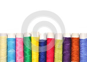 Pile of coloured bobbins of lurex thread isolated on white