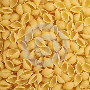 Pile of conchiglie yellow pasta as abstract background