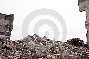 A pile of concrete fragments of construction debris against the background of the remains of the building. Background