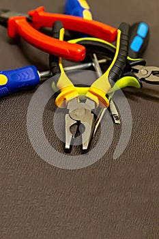 Pile of construction hand tools bright pliers nippers screwdriver on a dark base design base industrial