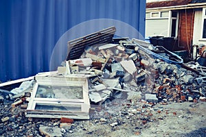A pile of construction waste near private house. Building rubble, bricks, stones. Junk, garbage piled up near the building. Street photo