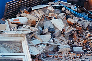 A pile of construction waste near private house. Building rubble, bricks, stones. Junk, garbage piled up near the building. Street photo