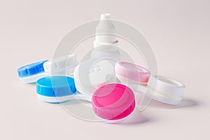 Pile of contact lens cases with white bottle on beige background