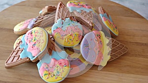 Pile of cookies with icing on wooden board.