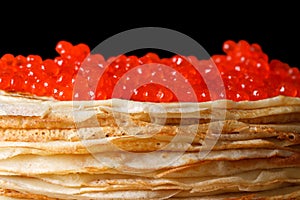 Pile of crepes with red caviar macro isolated on black