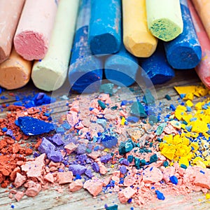 Pile of crushed chalk closeup and rainbow colored pastel crayons