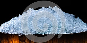 Pile of crushed ice cubes in wood bucket on dark background with copy space. Crushed ice cubes foreground for beverages, beer photo