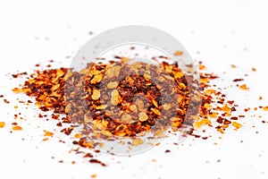 Pile crushed red cayenne pepper, dried chili flakes and seeds isolated on white background