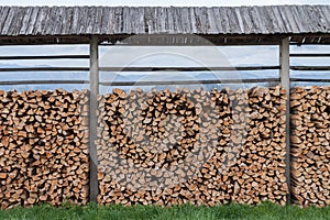 Pile of cut wood logs, neatly stacked outdoors under a shelter in Slovenia