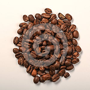 Pile of dark roasted coffee beans on white background