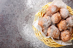 Pile of delicious oliebollen deep-fried raisin bun with powdered sugar closeup in the basket. Horizontal top view