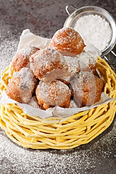 Pile of delicious oliebollen deep-fried raisin bun with powdered sugar closeup in the basket. Vertical