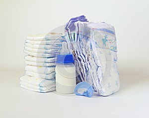 Pile of diapers and baby bottles on white background.