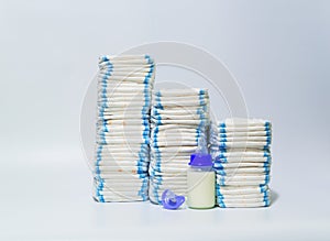 Pile of diapers and baby bottles on white background.