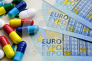 Pile of of different colouful pills placed next to 20 euro banknotes. Illustrative for cost of medical bills, health insurance and