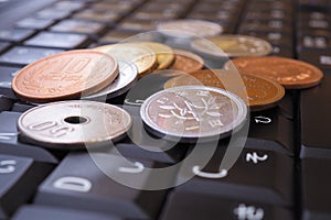 A pile of different Japanese coins lies on a black keyboard of a computer or laptop. Denomination is 1, 10, 50 yen. Online trading