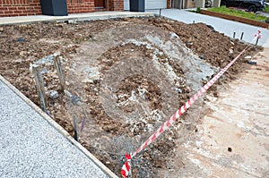 A pile of dirt in a small front yard of a new house with the barrier tape. An incomplete landscaping project