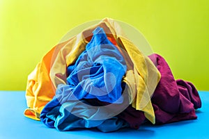 Pile of dirty laundry clothes on blue table Yellow background