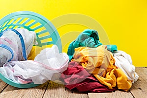Pile of dirty laundry in washing basket on wooden,yellow background.