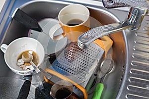 A pile of dirty and unwashed dishes in the sink close-up