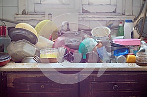 Pile of dirty utensils in a kitchen washbasin