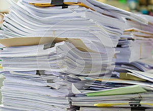 Pile of documents on desk stack up high waiting to be managed