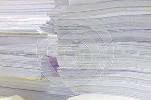 Pile of documents on desk stack up high waiting to be managed