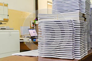 Pile of documents on desk stack up high waiting to be managed