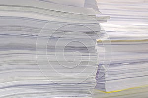 Pile of documents on desk stack up high waiting to be managed