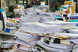 Pile of documents on desk stack up high waiting to be managed photo