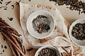 Pile of dried green tea leaves in little bowls, white background, dried tea leaves