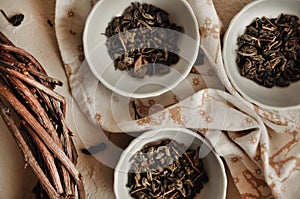 Pile of dried green tea leaves in little bowls, white background, dried tea leaves