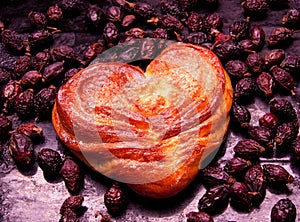 Pile of dried rose hips and Walnuts . Yeast sweet buns in the shape of a heart . Country house style. Authentically. photo