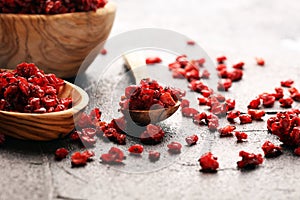 Pile of dry barberries in a wooden bowl on rustic table