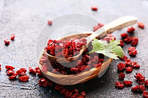 Pile of dry barberries in a wooden bowl on rustic table