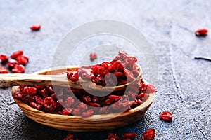 Pile of dry barberries in a wooden bowl on rustic table