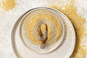 Pile of Dry uncooked bulgur wheat grain with a scoop on a plate top view. Healthy food