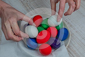 Pile of Easter eggs of different colors are stacked on a white plate. Easter eggs for Easter holiday. Christian faith and