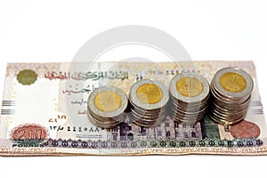 Pile of 200 EGP LE two hundred Egyptian pounds money banknotes with stacks of 1 LE EGP one pound coins isolated on white