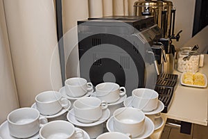 Pile of empty clean coffee cups mugs on shelf or coffee machine in cafe indoors.