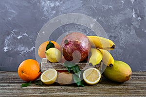 A pile of exotic fruits bananas, oranges, kiwi, pomegranate, mango, guava, lemon in a wooden box